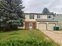 Two-story home featuring a two-car garage, front yard with a tree, solar panels and a brick entryway at 16405 E Kentucky Ave, Aurora, CO 80017
