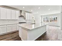 Bright, spacious kitchen features white cabinets, stainless hood, stone countertops, and a large center island at 2596 Bailey Ln, Erie, CO 80026