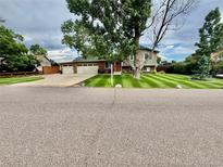 Charming two-story home featuring a beautifully manicured lawn and a two car garage at 8700 S Ammons St, Littleton, CO 80128