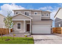 Charming two-story home with a well-manicured lawn and a classic craftsman-style front porch at 48295 Shetland Dr, Bennett, CO 80102