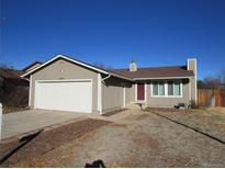 Tan one-story house with attached garage and red front door at 16757 E Mansfield Cir, Aurora, CO 80013