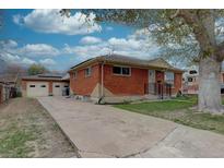 Charming brick home featuring a long driveway leading to a detached two-car garage and landscaped front yard at 7747 Quivas St, Denver, CO 80221