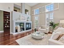 Bright living room featuring a fireplace with built-ins, hardwood floors, and large windows with shutters at 3773 S Dayton Way, Aurora, CO 80014