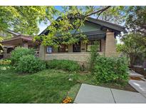 Charming home featuring a brick facade, covered porch, and lush landscaping in a desirable neighborhood at 756 Steele St, Denver, CO 80206