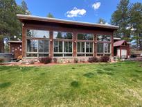 Stunning exterior showcasing modern architecture, large windows, stone accents, and lush green lawn at 720 N Bluff Dr, Franktown, CO 80116