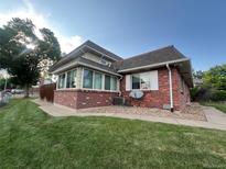 Charming brick home featuring a sunroom, manicured lawn, and mature trees at 9762 Appletree Pl, Thornton, CO 80260