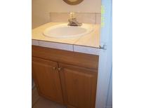 Bathroom sink with a tile countertop and wood cabinets below create a functional space at 10742 E Exposition Ave # 124, Aurora, CO 80012