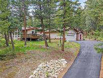 Charming exterior of home featuring a deck, garage, and scenic wooded surroundings at 7585 Native Dancer Trl, Evergreen, CO 80439