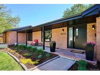 Inviting front entrance with a well-manicured garden, brick facade, and a cozy seating area on the covered porch at 3666 S Jersey St, Denver, CO 80237