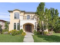 Elegant stucco home featuring manicured lawn, stone archway, second story balcony and lush landscaping at 2362 Spruce Way, Denver, CO 80238