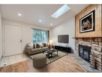 Bright living room featuring a stone fireplace, skylight, and sliding glass doors to a balcony at 63 S Sable Blvd # E22, Aurora, CO 80012