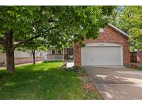 Charming single-Gathering home with a brick facade, two car garage, lawn, and mature shade tree at 1901 S Union Pl, Lakewood, CO 80228