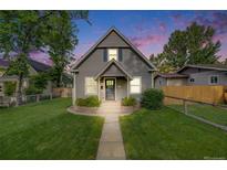 Charming gray home with a well-manicured lawn and lovely landscaping under a beautiful colorful sunset sky at 3881 Zenobia St, Denver, CO 80212