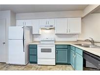 Bright kitchen features white subway tile backsplash and white and teal cabinets at 7260 S Gaylord St # E26, Littleton, CO 80122