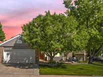 Charming home featuring a well-manicured lawn, mature trees, and a cozy outdoor seating area at 8915 W Quarto Pl, Littleton, CO 80128
