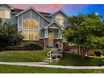 Charming townhome with brick accents, well-manicured lawn, and inviting entryway staircase at 18489 E Columbia Cir, Aurora, CO 80013