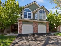 A well-maintained green townhouse with two garage doors and arched windows on a sunny day at 2418 W 82Nd Pl # D, Westminster, CO 80031
