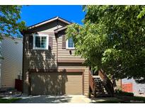 Charming two-story home with attached garage, wood siding, and neatly landscaped front yard at 293 Wagonwheel Dr, Fort Lupton, CO 80621