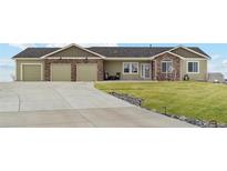 Charming single-story home featuring a three-car garage, stone accents, and a well-maintained lawn at 39200 E 148Th Ct, Keenesburg, CO 80643
