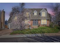 Charming brick home with manicured lawn, blooming tree, and grey roof with dormer windows at 5490 S Jellison St, Littleton, CO 80123