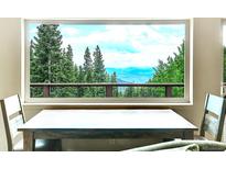 Inviting dining area showcases spectacular views of mountains and trees through large window at 1176 Raven Ridge Rd, Idaho Springs, CO 80452