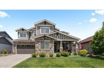Beautiful two-story home showcasing stone accents, a well-manicured lawn, and a charming front porch with seating at 20293 E Shady Ridge Rd, Parker, CO 80134