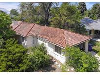 Aerial view showcasing a single-story home with a unique tile roof, lush greenery, and a spacious garage at 6235 E 6Th Avenue Pkwy, Denver, CO 80220