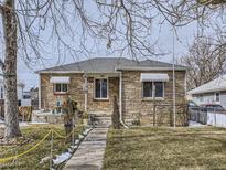 Ranch style home with stone exterior, walkway, and mature trees at 1333 Hanover St, Aurora, CO 80010