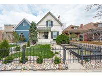 Charming two-story home with a manicured front yard, fence and rock details at 568 Galapago St, Denver, CO 80204