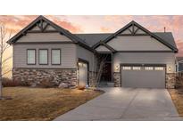 Beautiful home featuring a three-car garage, stone accents, and a well-manicured lawn at 1839 Pinion Wing Cir, Castle Rock, CO 80108