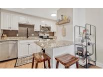 Bright kitchen features stainless steel appliances, granite countertops, and an eat-in island with seating for two at 2500 S York St # 102, Denver, CO 80210