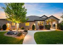 Charming brick home featuring a well-manicured lawn, illuminated walkway, and inviting front entrance at 13087 W 27Th Ln, Golden, CO 80401