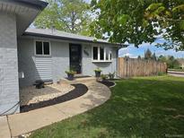 Charming home featuring a landscaped front yard, gray brick exterior, and a concrete walkway leading to the front door at 795 Vivian Ct, Lakewood, CO 80401