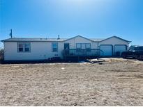 Ranch-style home with a two-car garage, deck, and a large front yard at 554 E Pleasant Ave, Byers, CO 80103