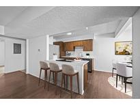 Open kitchen with a breakfast bar, wood cabinets, modern appliances, and a dining area at 7665 E Eastman Ave # D304, Denver, CO 80231