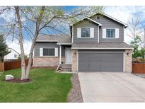 Charming two-story home features a well-maintained lawn and a classic gray exterior with brick accents at 13093 Hudson St, Thornton, CO 80241