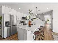 Modern kitchen features stainless steel appliances, white cabinetry, and a large island with stylish seating at 1337 N Alton St, Aurora, CO 80010