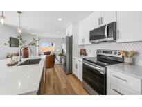 Modern kitchen with white cabinets, stainless steel appliances, and quartz countertops open to the living room at 1337 N Alton St, Aurora, CO 80010