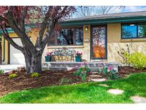 Charming brick home featuring a bench on the porch and a beautifully landscaped front yard with colorful flowers at 5485 S Lakeview St, Littleton, CO 80120