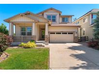 Charming two-story home with landscaped front yard, covered porch, and attached two-car garage at 13794 E Caley Dr, Englewood, CO 80111