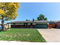 Charming ranch-style home with a well-manicured lawn, brick accents, and an attached garage at 16291 E 7Th Dr, Aurora, CO 80011