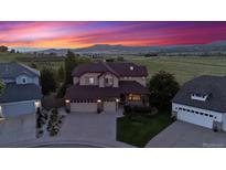 Stunning two-story home with a three-car garage, mature landscaping, and mountain views at sunset at 4099 Starflower Rd, Castle Rock, CO 80109