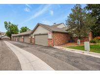Brick townhome featuring attached garages and manicured lawn under a blue sky with some clouds at 4231 S Fairplay Cir # A, Aurora, CO 80014