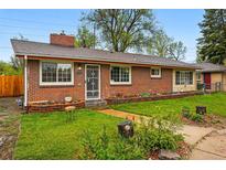Charming single-story brick home featuring a well-manicured lawn and landscaped garden beds, creating a welcoming curb appeal at 8736 W 46Th Ave, Wheat Ridge, CO 80033