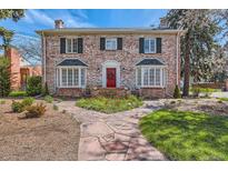 Charming brick home with red door, bay windows, landscaped yard, and a stone walkway leading to the front entrance at 1000 N Monaco Pkwy, Denver, CO 80220