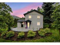 Charming home boasts colorful accents, a cozy front patio, and a well-maintained landscaped yard at 5071 Parmalee Gulch Rd, Indian Hills, CO 80454