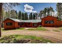 Charming cabin exterior with wood siding, green metal roof, and detached garage in a wooded setting at 9123 Booker Ln, Conifer, CO 80433