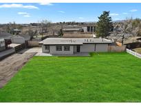 Attractive home with a large, manicured lawn, gray stucco, and a detached garage in the rear at 9950 W 17Th Ave, Lakewood, CO 80215