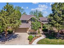 Charming two-story home featuring a brick facade, attached garage, and beautifully landscaped front yard with mature trees at 5373 E Links Cir, Centennial, CO 80122
