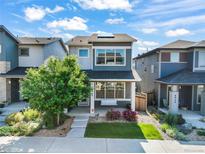 Charming two-story home boasts a cozy front porch swing and a well-manicured front yard at 6940 Clay St, Denver, CO 80221